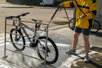 Fototapeta na wymiar young man washing bicycle at carwash. lifestyle