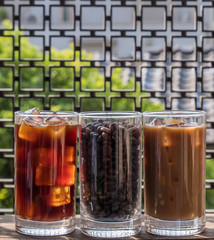 Black iced coffee, milk coffee, and beans over wooden background