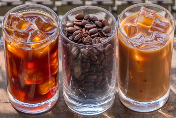 Black iced coffee, milk coffee, and beans over wooden background