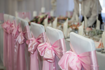 White chairs are decorated with a pink tape