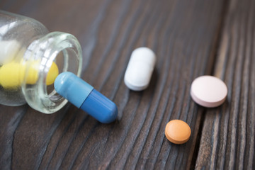 medical tablets poured from a flask on a wooden background