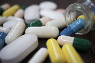 medical tablets poured from a flask on a wooden background