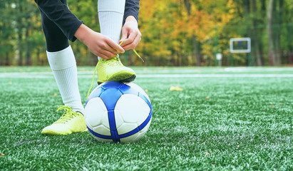 Boy football soccer tying the laces on the boots on grassy football stadium. - 206665661