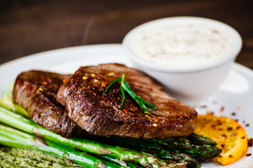 Grilled beefsteak with asparagus on wooden background