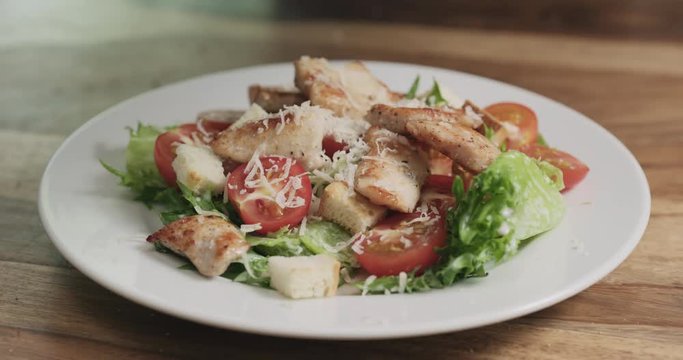 Slow motion closeup parmesan flakes falling on caesar salad