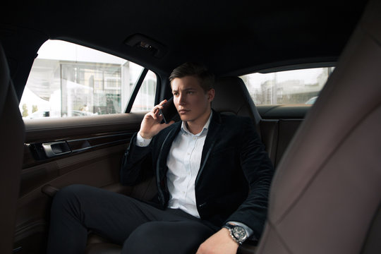 Serious boss! Young smart male professional businessman seriously talking on smartphone, while going to the office by car.