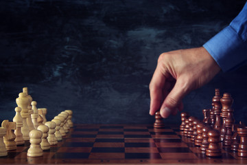 Image of businessman hand moving chess figure over chess board. Business, competition, strategy, leadership and success concept.