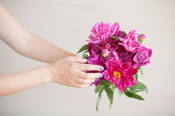 Beautiful bright bouquet of peonies. Female hands gently touch the flowers.