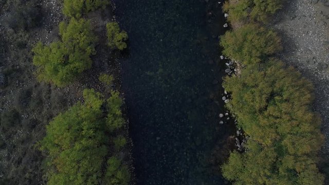 Aerial drone top view scene of Pulmari river in autumn with trees at the edge, stream, rocks. Camera moving backwards.