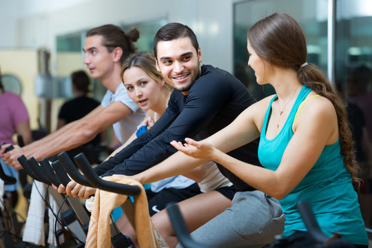 Young adults on exercise bikes in gym.