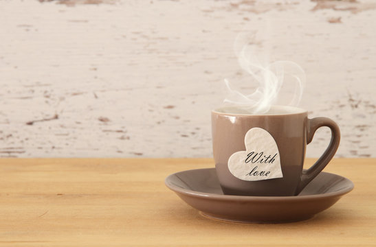 image of coffe cup with heart over wooden table.