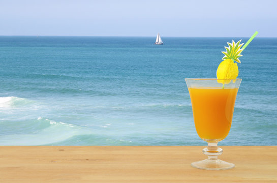 image of tropical and exotic fruit coctail over wooden table infront of sea landscape background.