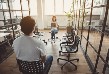 Orderly girl telling with colleague while making notes. He turning back to camera