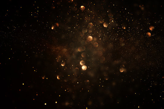 glitter vintage lights background. dark gold and black. de focused.