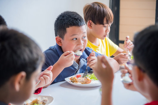 Young asian boy having lunch with friends at school canteen