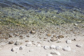 sea clear water of beautiful blue-green shades, stones and light sand on the shore