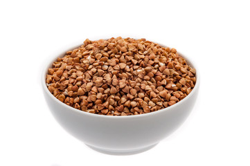 Buckwheat groats in a white cup close-up on a white background. Isolated.
