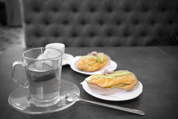 Close-up of tea and pastries on table, black and white picture with colored pastries
