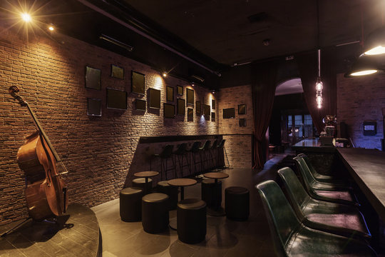 Modern jazz bar interior design, stage with cello, lamps above bar counter