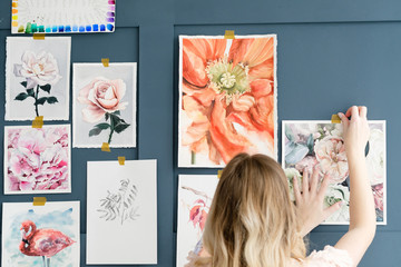 Naklejka premium creative leisure. painting hobby. artful personality. talented girl sticking her watercolor drawings to the wall