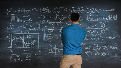 Brilliant Young Mathematician Approaches Big Blackboard and Thinks about Solving Long and Complex Equation/ Formula.