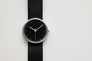 Minimalist wristwatch black dial on white background