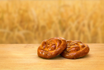 Fresh baked bread on wooden table on a background wheat field in period harvest