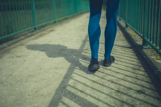 Feet and legs of young woman walking on foot bridge