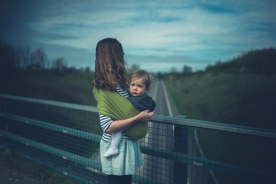 Young mother with baby on road bridge