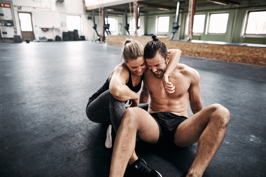 Affectionate young couple sitting in a gym after working out