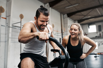 Fototapeta na wymiar Smiling woman cheering on her gym partner riding a bike