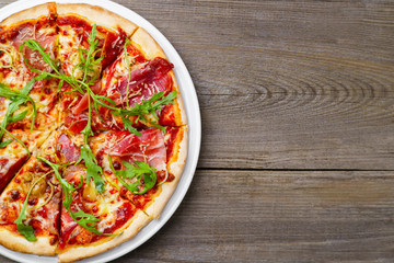 Italian pizza background with prosciutto and arugula, copy space. Italian food, pizzeria, restaurant menu concept.