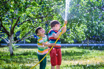 Brothers having fun splash each other with water in the village