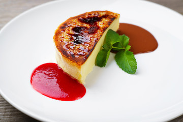 Sweets, confectionery, pastry, desserts. Cheesecake with strawberry and chocolate sauce on porcelain plate