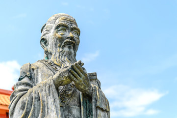 closeup old statue of confucius with soft-focus and over light in the background - obrazy, fototapety, plakaty