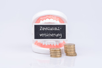 Zahn Gebiss mit Euro Münzen und einem Schild Zahnzusatz Versicherung
