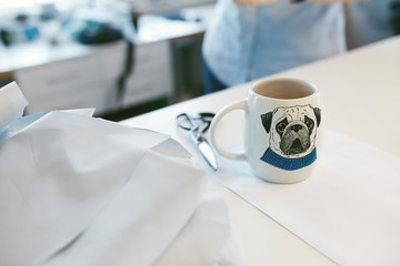 Cup Of Coffee On Tailor's Table In Atelier