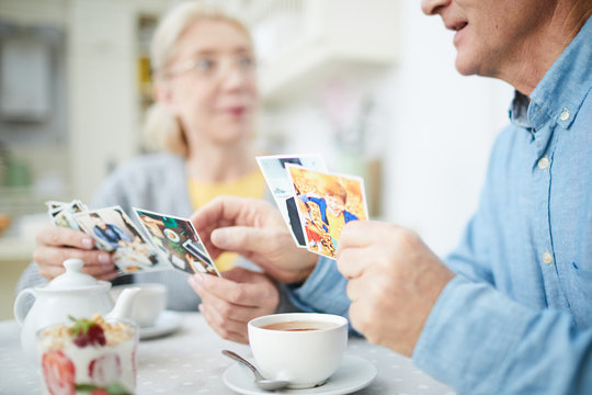 Senior man and woman looking through photos of their grandchildren while having tea