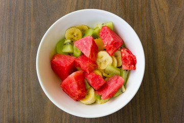 Delicious, healthy fruit salad bowl for breakfast. Dessert on wood background