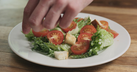 closeup adding croutons to caesar salad
