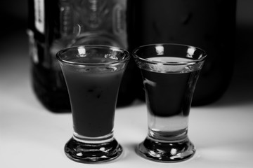 Glasses and bottle with tequila and sangrita isolated close-up in black and white tones background. Sangrita mexican traditional drink as analogue bloody mary