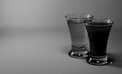 Two glasses with tequila and sangrita isolated in black and white tones on grey background. Copy space