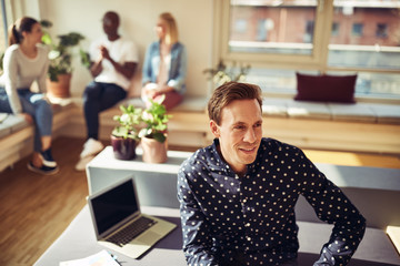 Smiling manager sitting on his desk in an office