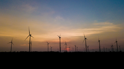 Wind turbine farm and agricultural fields with rays of light at sunset