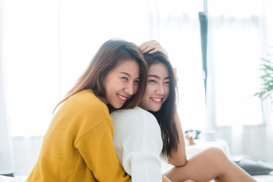 Beautiful young asian women LGBT lesbian happy couple sitting on bed hugging and smiling together in bedroom at home. LGBT lesbian couple together indoors concept. Spending nice time at home.