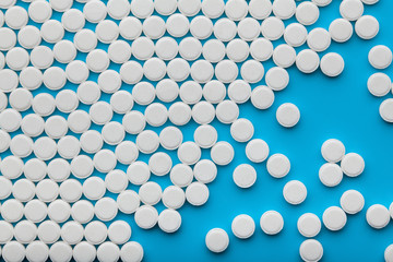 White pills on blue background, copy space
