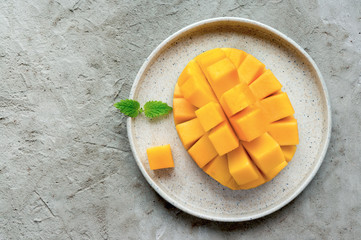 Healthy breakfast. Sliced mango fruit on plate. Top view. Concrete background. Minimal food photo. 