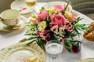 Festive table with flower bouquet and porcelain dining set.