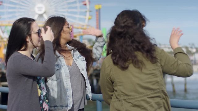 Group Of Friends Point Out Sights At Santa Monic Pier, Amusement Park Rides In Background (Shot On Red Scarlet-W Dragon In 4K, Slow Motion)