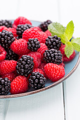 Fresh raspberries in a plate on a  vintage background.